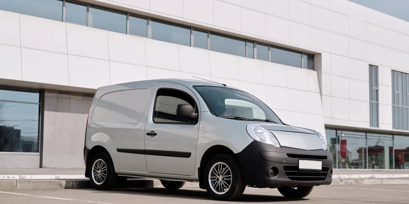 Unbranded white courier van outside a modern city office